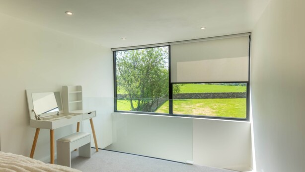 A modern bedroom with a large window, a bedside table, and a mirror. - The Studio @ Cherry Tree (Natland)