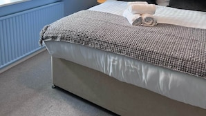 A bedroom with a bed, a window with curtains, a bedside lamp, and a headboard. - The House at Cherry Tree (Kendal)