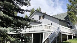 A two-story house with a covered porch and a staircase leading to the entrance. - Trail and Tide-Sleeps 18- Hot tub and Game Room (Island Park)
