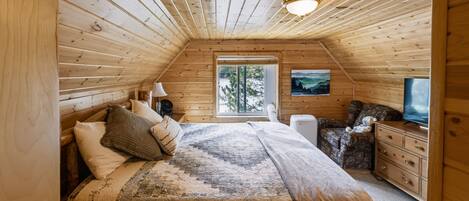A cozy bedroom with a bed, dresser, and a television.