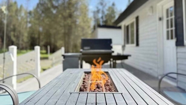 A wooden deck with a built-in fire feature, a barbecue grill, and a pool. - Trail and Tide-Sleeps 18- Hot tub and Game Room (Island Park)