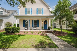 A two-story house with a front porch, a blue door, and a number '110' on the front. - Tide and Time Again charming 3-bedroom coastal home in historic Old Town Bluffton (Bluffton)