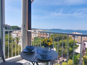 Ein Balkon mit Esstisch, der Blick auf die Küste freigibt.