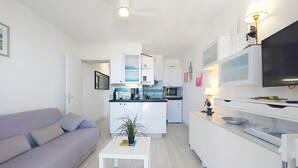 Moderni huoneisto, jossa on olohuone, pieni keittiö ja ruokailutila.