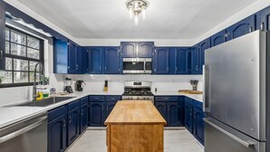 Een moderne keuken met blauwe kastjes, roestvrijstalen apparatuur en een houten eiland.
