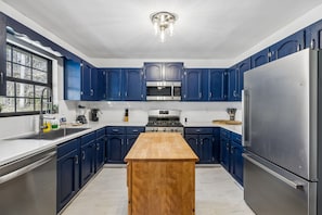 A modern kitchen with blue cabinets, stainless steel appliances, and a wooden island. - Emerald Woods Hangout | Spacious, Pet Friendly, Fire Pit (Sevierville)