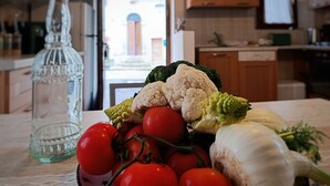 A kitchen counter with a variety of fresh vegetables including tomatoes, broccoli, cauliflower, and garlic. - Federico's Cantuccio, cozy apartment in the heart of Radicofani (Radicofani)