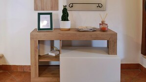 A wooden console table with a framed certificate, a potted plant, and a small decorative item. - Federico's Cantuccio, cozy apartment in the heart of Radicofani (Radicofani)