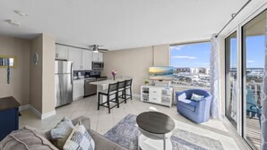 A modern apartment with a kitchen, dining area, and a balcony with a city view. - Sky High View at EB& Tennis 1002C-NEW LISTING (Fort Myers Beach)