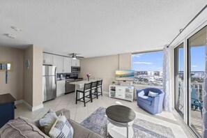 A modern apartment with a kitchen, dining area, and a balcony with a city view. - Sky High View at EB& Tennis 1002C-NEW LISTING (Fort Myers Beach)