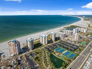 Ein Küstenwohngebiet mit Hochhäusern, einem Strand und einem Tennisplatz.