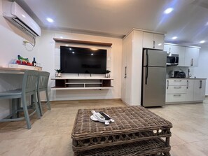 Una cocina moderna con armarios blancos, un microondas integrado y un refrigerador de acero inoxidable.