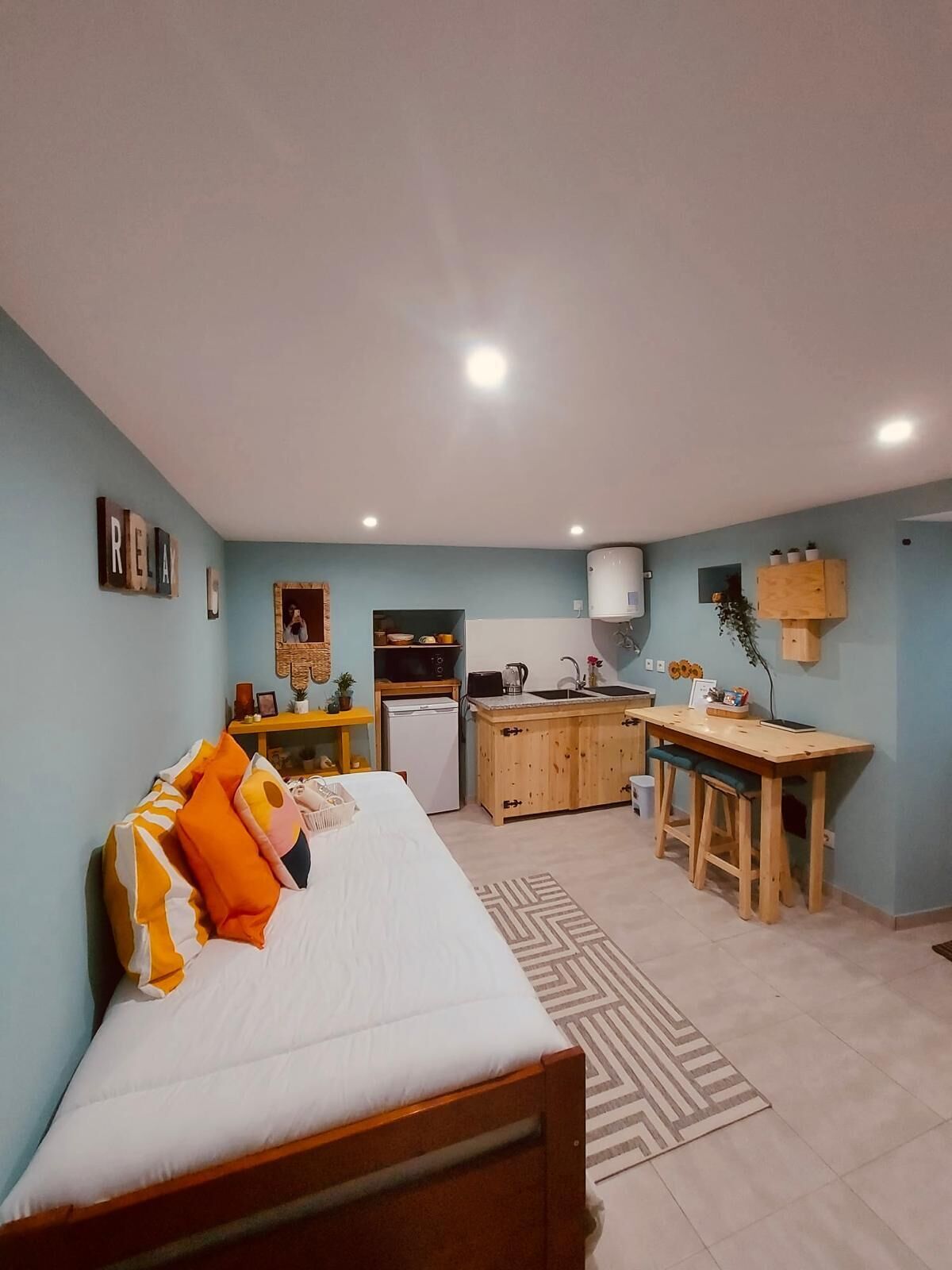 Ein kleines Zimmer mit einem Bett, einer Küchenzeile und einer Essecke.