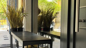 Un interior moderno con una mesa de metal y plantas en macetas, una puerta con manija y vistas a la calle.