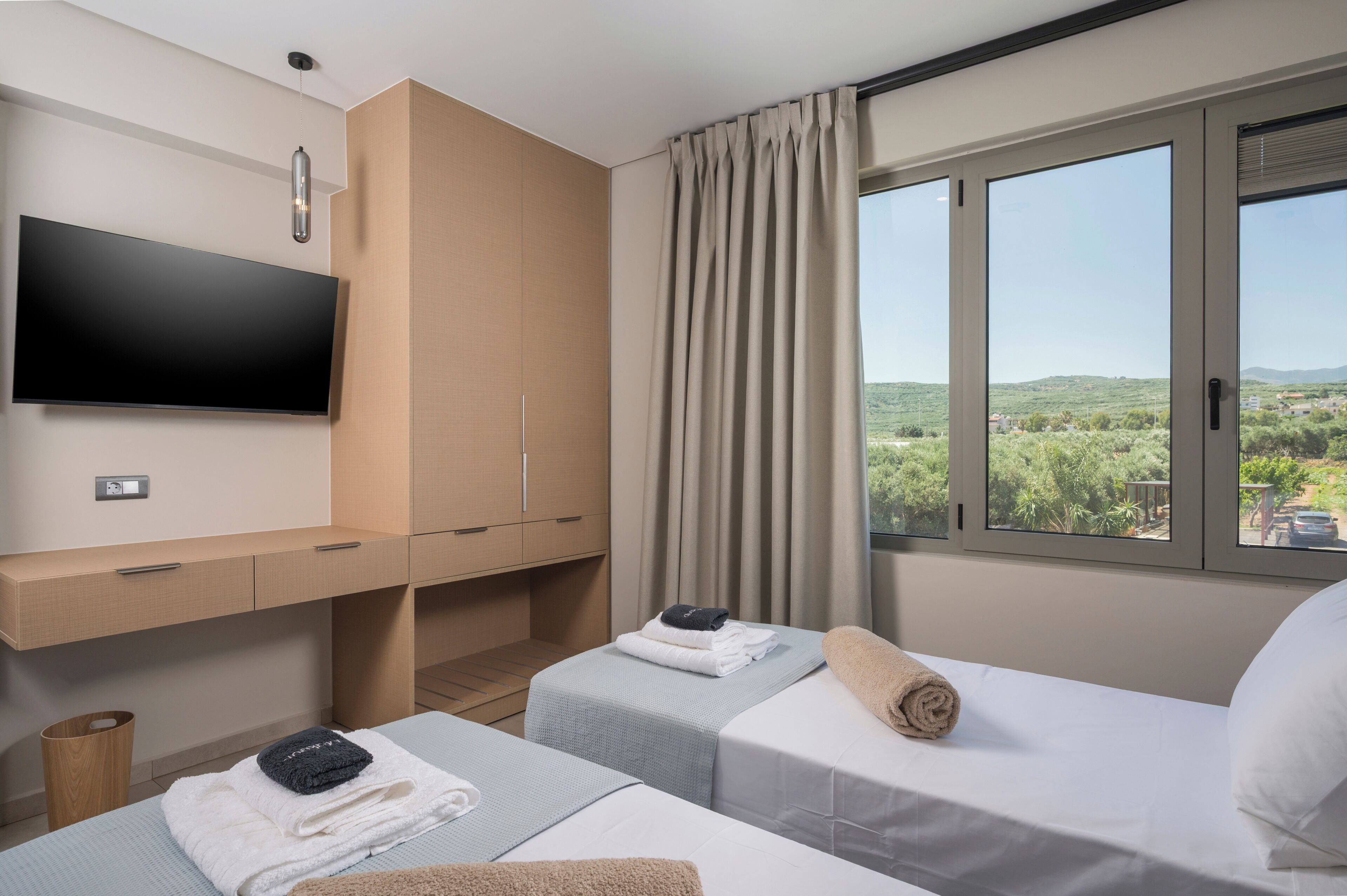 A hotel room with a bed, a TV, a desk, and a window with a view.