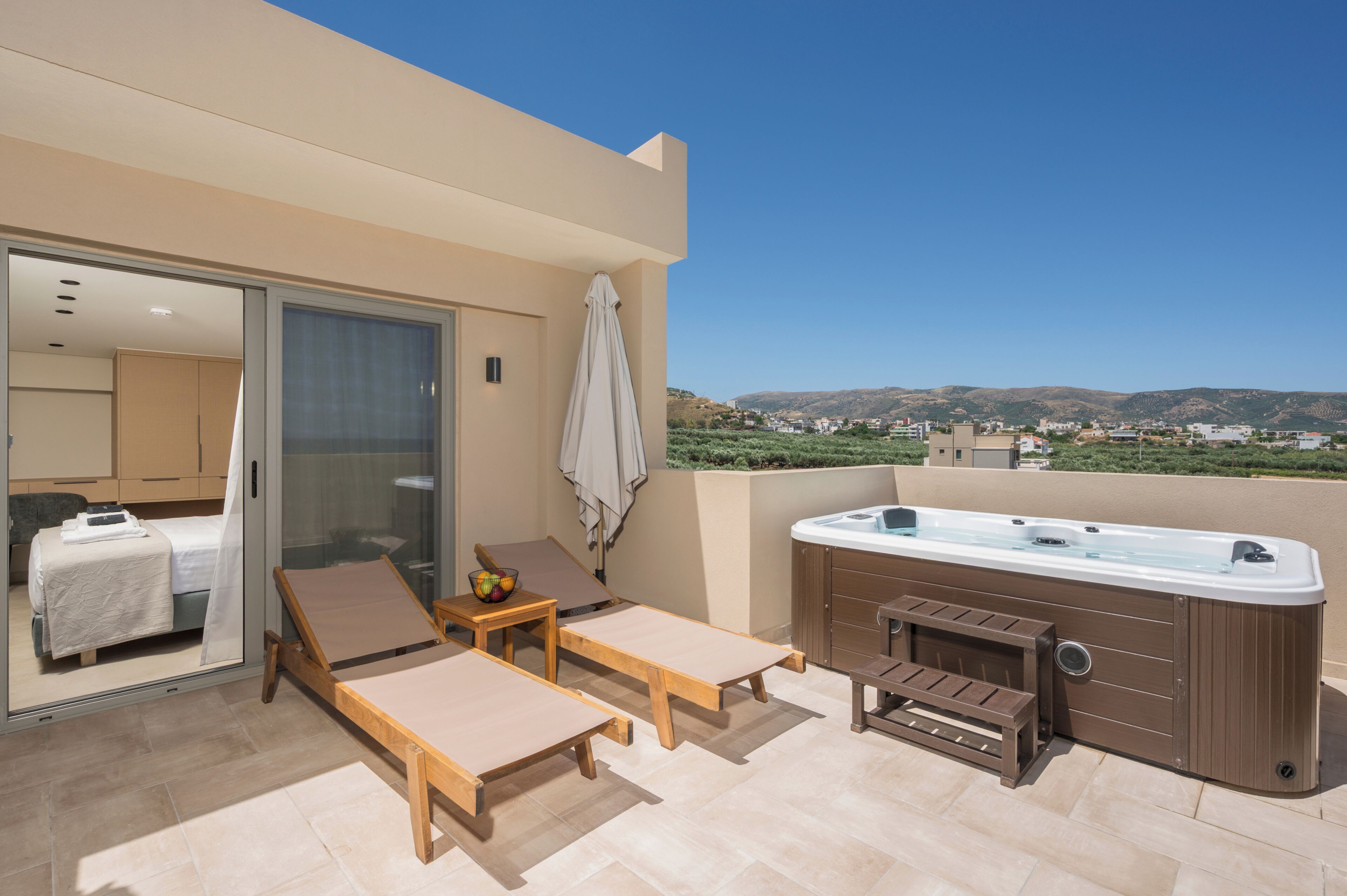 A balcony with a hot tub, lounge chairs, and a view of the landscape.