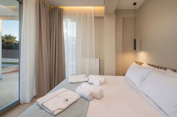 Une chambre d’hôtel avec un lit, des serviettes, une fenêtre avec des rideaux et un luminaire suspendu.