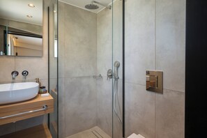 A modern bathroom with a glass-enclosed shower, a sink with a wooden countertop, and a mirror. - The New Life Houses (Kissamos)