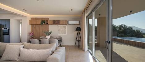 Un saló modern amb un sofà, una zona de menjador i vistes a l'exterior.