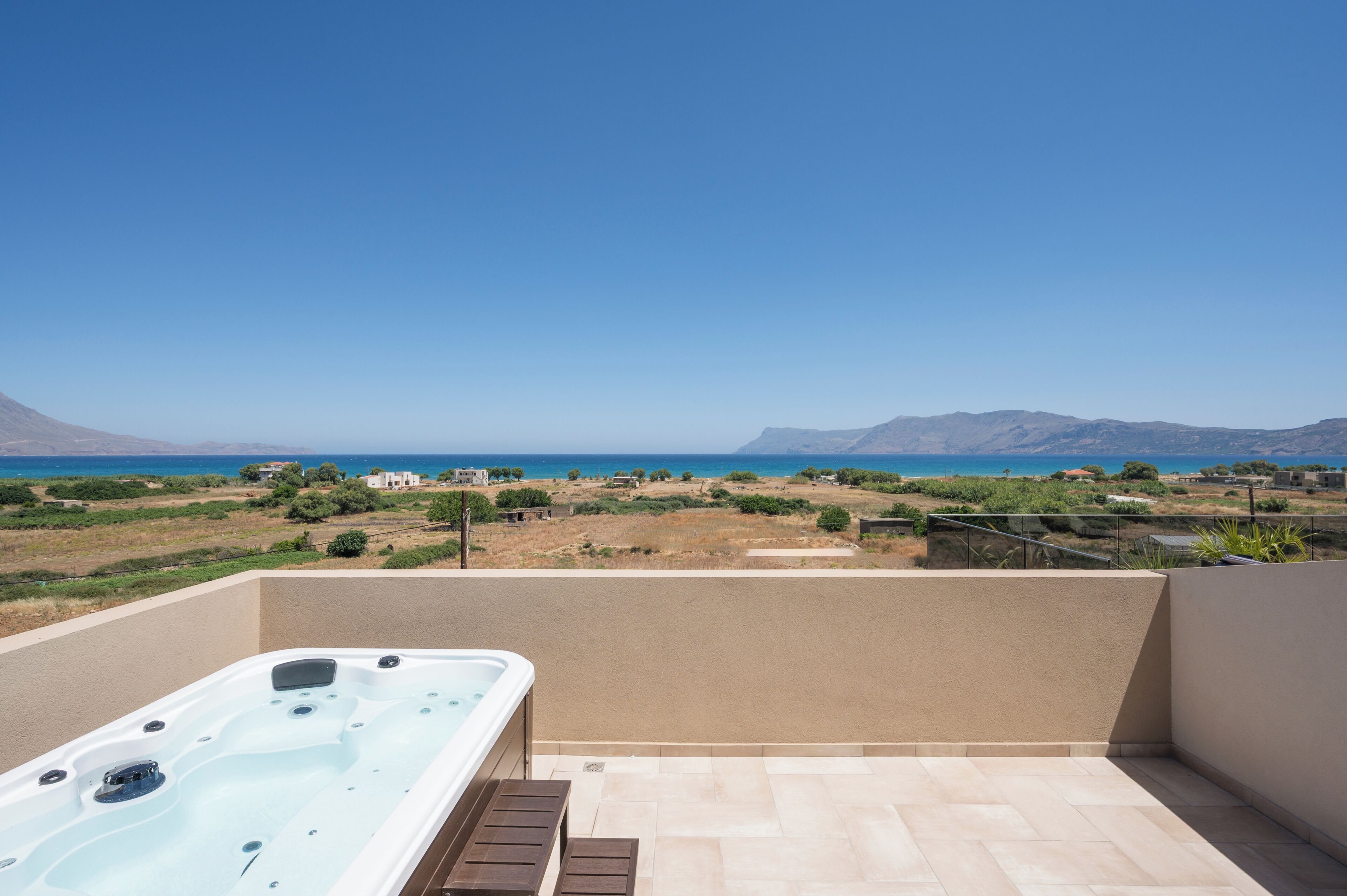A hot tub on a balcony with a view of the sea and mountains.