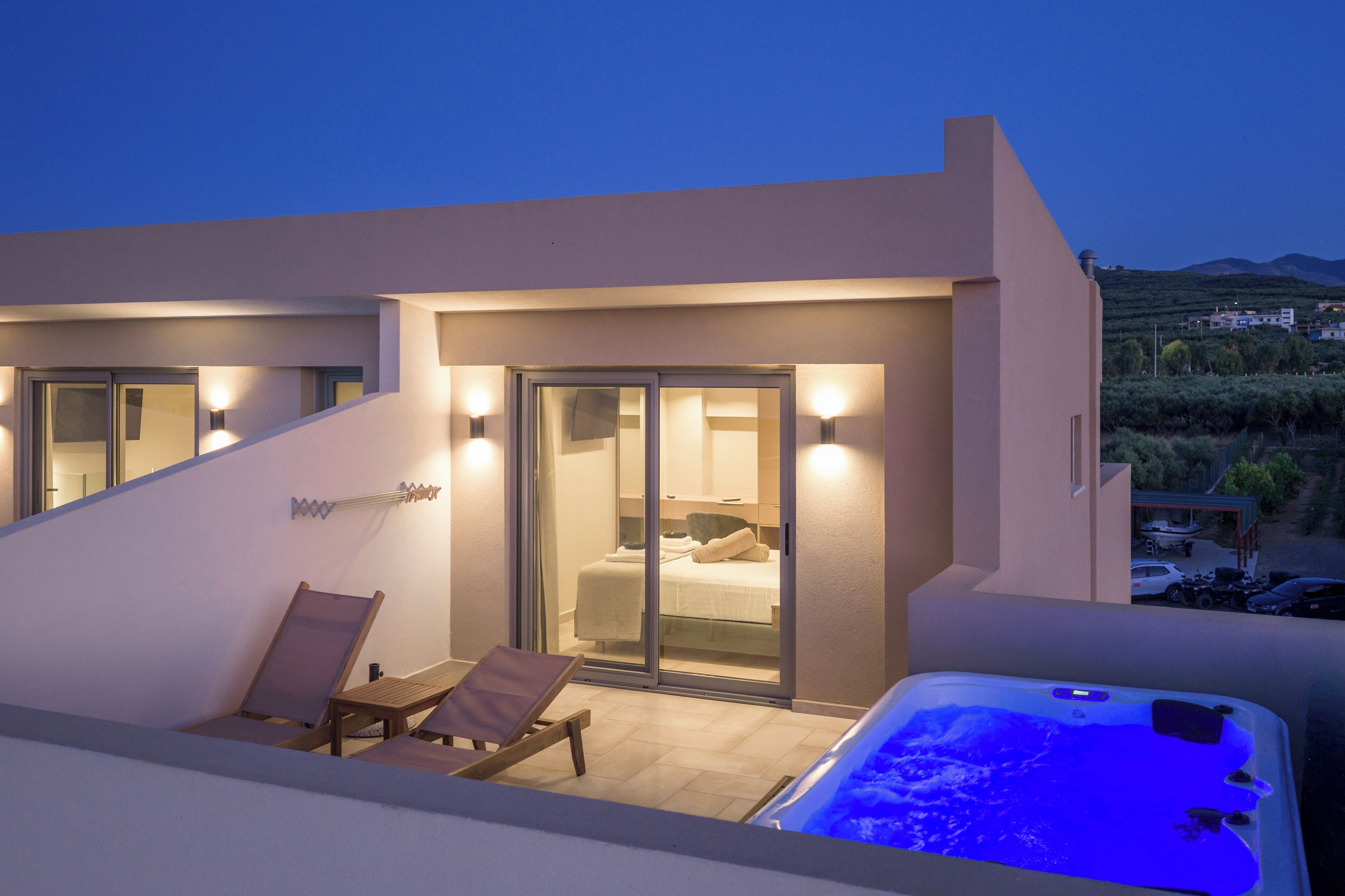 Une chambre d’hôtel moderne dotée d’une porte-fenêtre, d’un jacuzzi et d’un balcon avec des chaises longues.