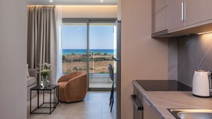 A modern kitchen with a view of the sea, a dining area with a chair, and a small table with a vase. - The New Life Houses (Kissamos)