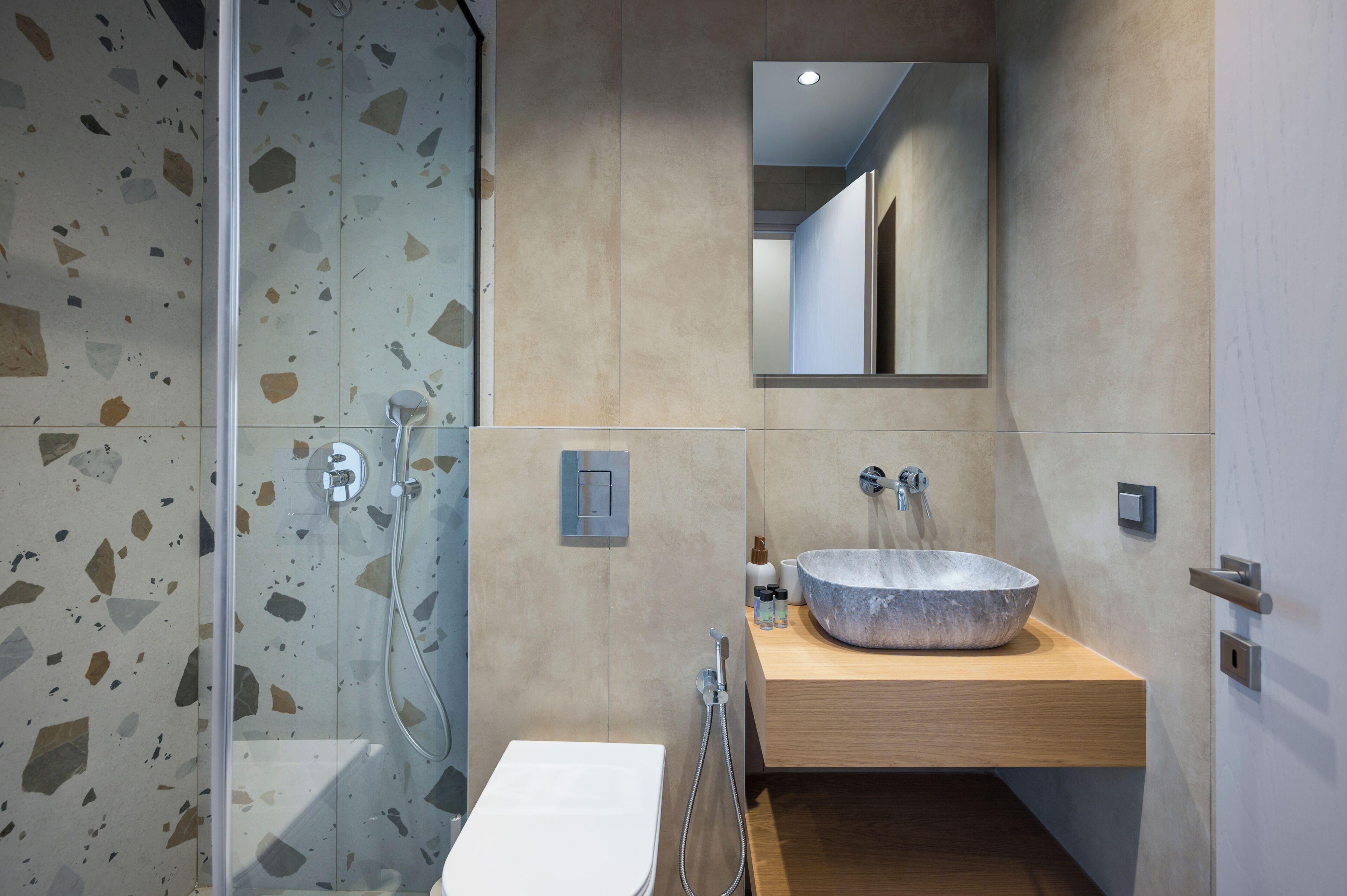 A modern bathroom with a glass shower enclosure, a freestanding sink with a large basin, and a mirror above the sink.