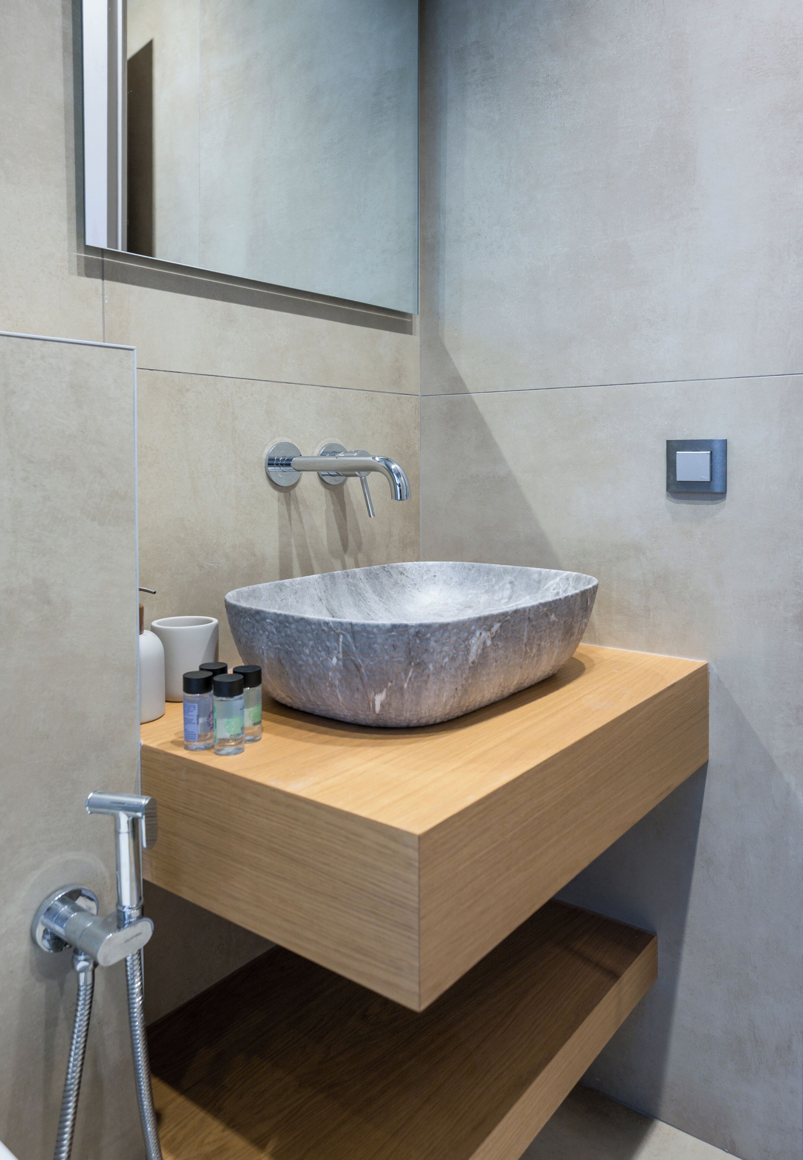 A modern bathroom with a large stone sink, wooden countertop, and a mirror above.
