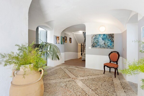 A spacious hallway with a stone floor, a chair, and a large painting on the wall. - Apartment Franca in Villa Pini with Shared Pool (Sarzana)