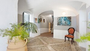 Ein geräumiger Flur mit Steinböden, einem Sessel und einem großen Gemälde an der Wand.