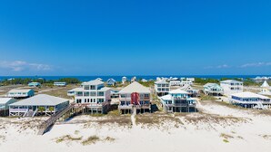 Um resort costeiro com propriedades na praia, incluindo edifícios com vários andares e varandas, e um prédio com telhado vermelho marcante.