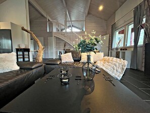 A modern living room with a sofa, a coffee table, and a vase with flowers.