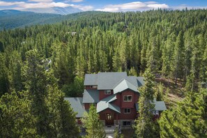A two-story lodge surrounded by dense forest, with a mountain in the background. - Summer Retreat by InvitedHome | BBQ, Hot Tub, Dog Friendly, 5 Min to Downtown (Breckenridge)