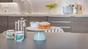 Una cucina moderna con un angolo caffè, che include una caffettiera a stantuffo, un teiera e una tazza da tè.