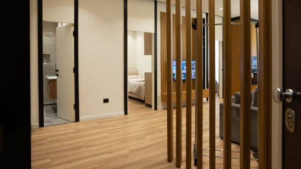 Una habitación de hotel moderna con piso de madera, una cama, un escritorio y un televisor.