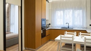 Una cocina moderna con armarios de madera, horno empotrado y comedor con mesa y sillas blancas.