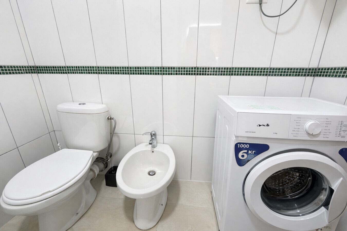 A small bathroom with a toilet, bidet, and a front-loading washing machine.