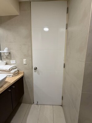 A bathroom with a white door, a sink, and a towel rack. - APT ATHELIER - BARRANCO  (Lima)