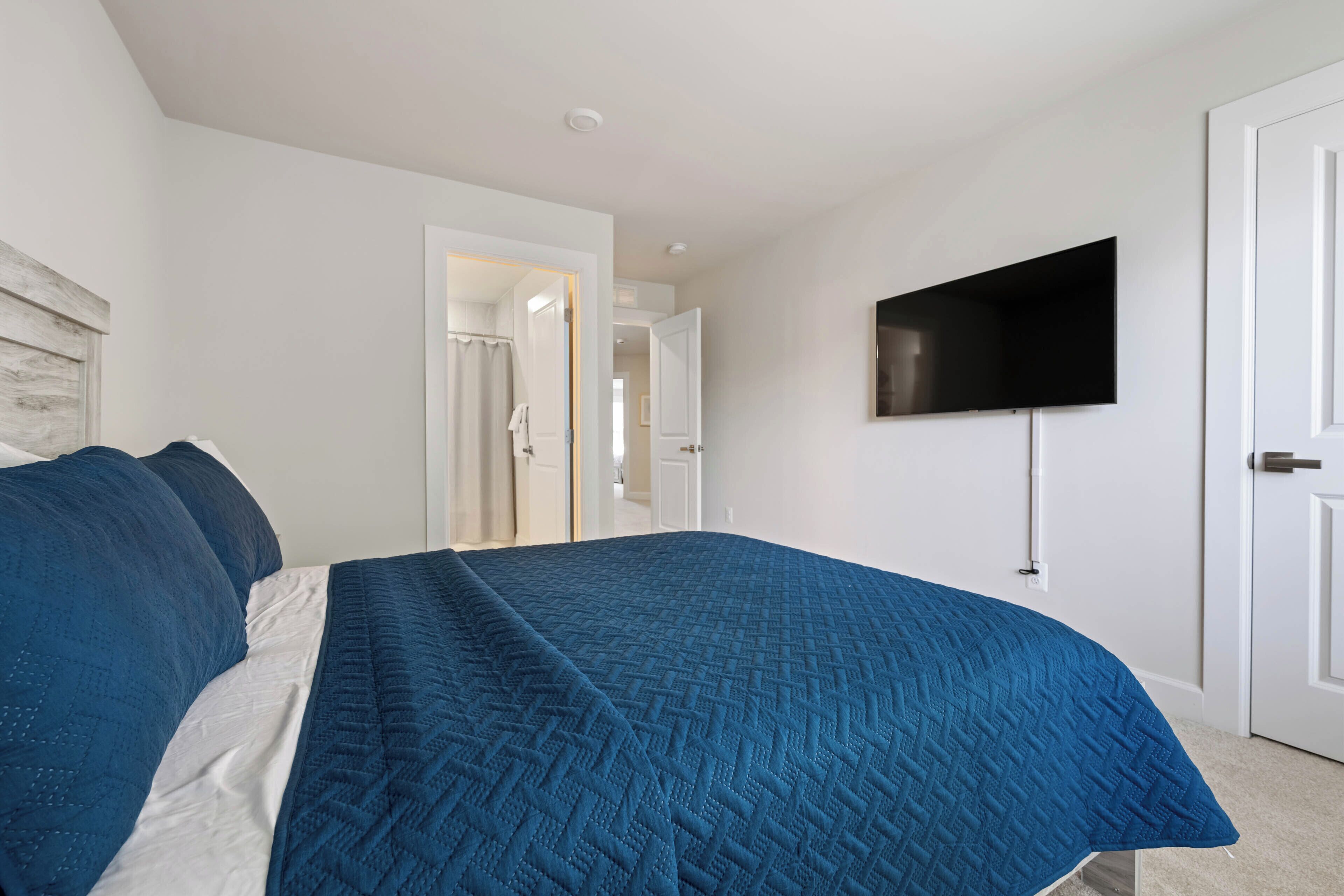 Une chambre à coucher avec un lit, un téléviseur fixé au mur et une porte.