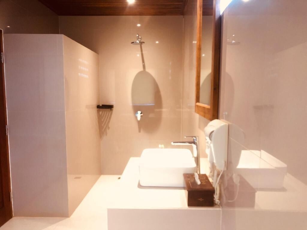 A bathroom with a glass shower enclosure, a white sink, and a mirror.