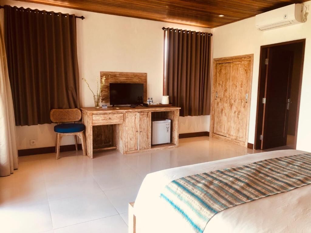 A hotel room with a bed, a desk with a computer, a chair, and a wardrobe.