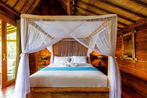 A wooden cabin room with a four-poster bed, a nightstand with a lamp, and a window with curtains. - Bali Natha Beach Front (Cemagi)