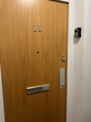 A wooden door with a metal handle, a keyhole, and a peephole. - Heathrow Airport - Apt - Stay 3 - Great Location (Hounslow)