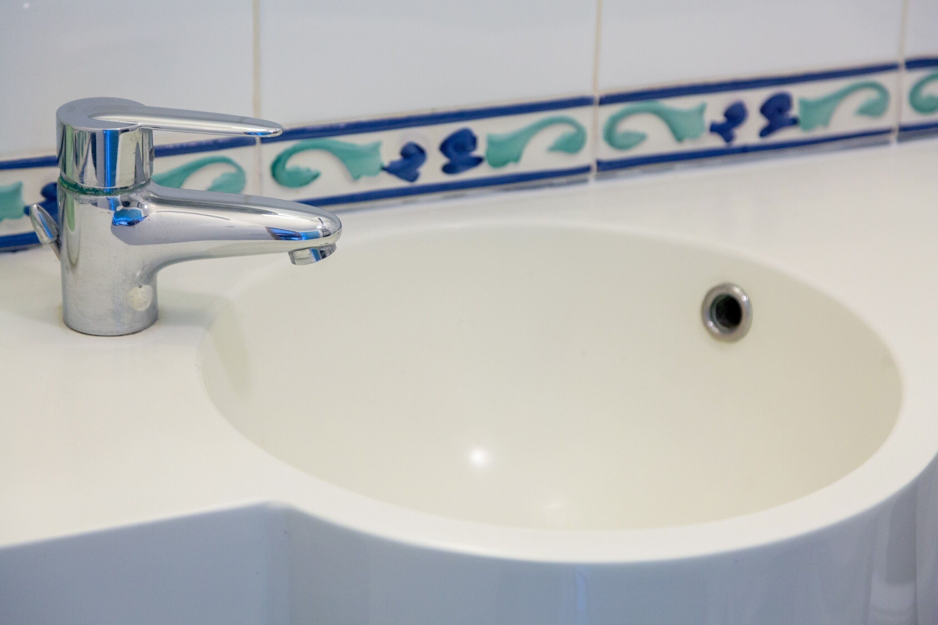 Ein Waschbecken mit chromfarbenem Wasserhahn und weißer Schüssel.