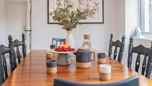 Een eettafel gedekt met taart, fruit en koffiemokken.