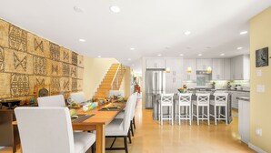 A modern kitchen with white cabinets, a stainless steel refrigerator, and a dining area with a wooden table and chairs. - Perfect For Families,Walk 2 Beach and Restaurants! (San Diego)