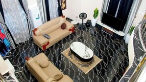 A modern living room with a sectional sofa, a coffee table, and a flat-screen TV. - Exclusive Holiday Villa in Umuahia (Umuahia)