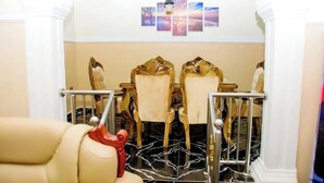 A hotel room with a plush beige sofa, a dining area with ornate chairs and a chandelier, and a marble floor. - Exclusive Holiday Villa in Umuahia (Umuahia)