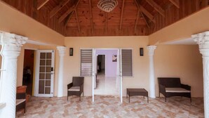 A spacious room with a high wooden ceiling, a chandelier, and a view into another room through a doorway. - Paradise Oasis - Ocho Rios (Tower Isle)