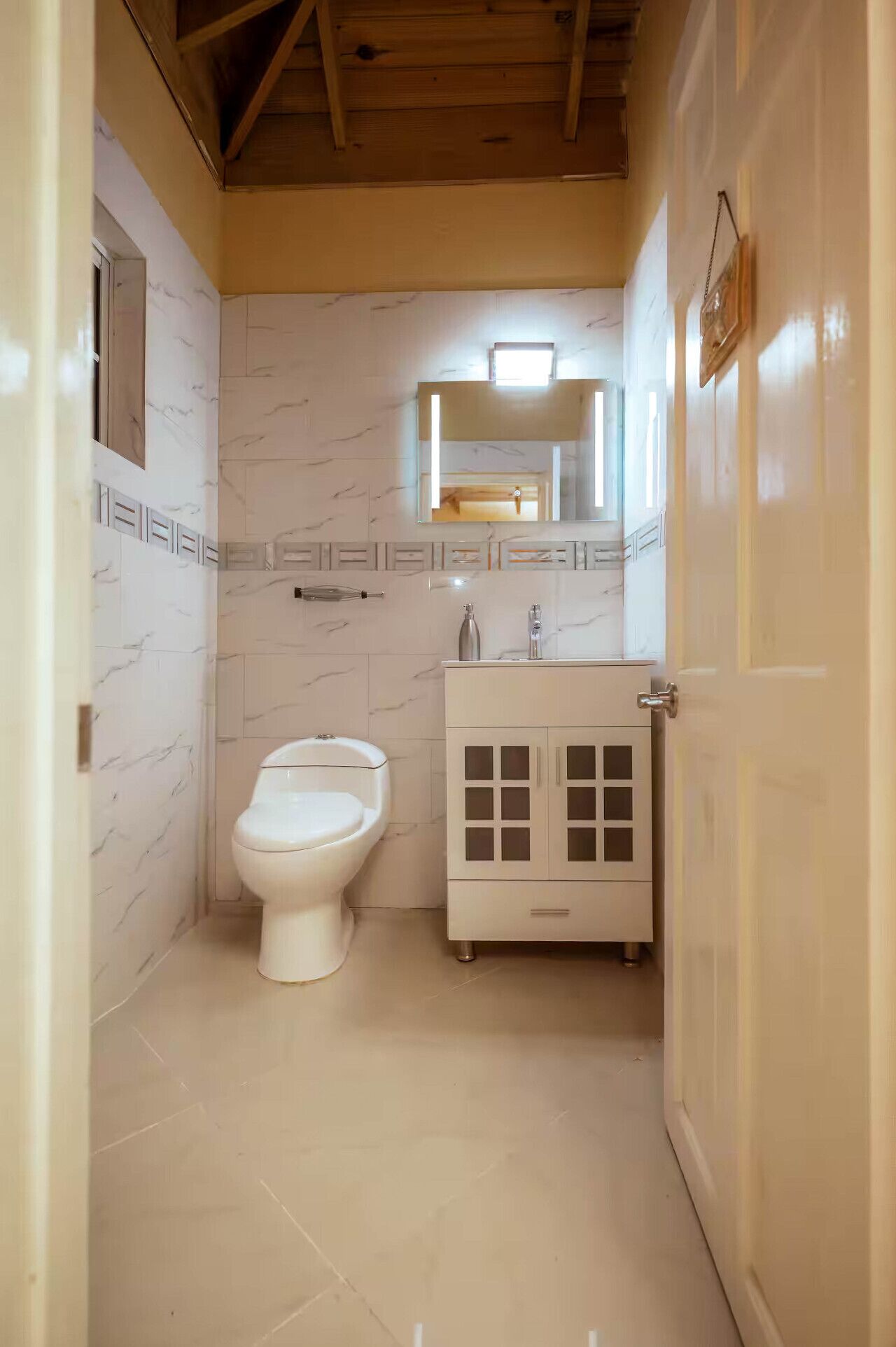 Ein kleines, kompaktes Badezimmer mit Toilette, einem Waschbecken mit Spiegel darüber und einem Schrank mit Schubladen.